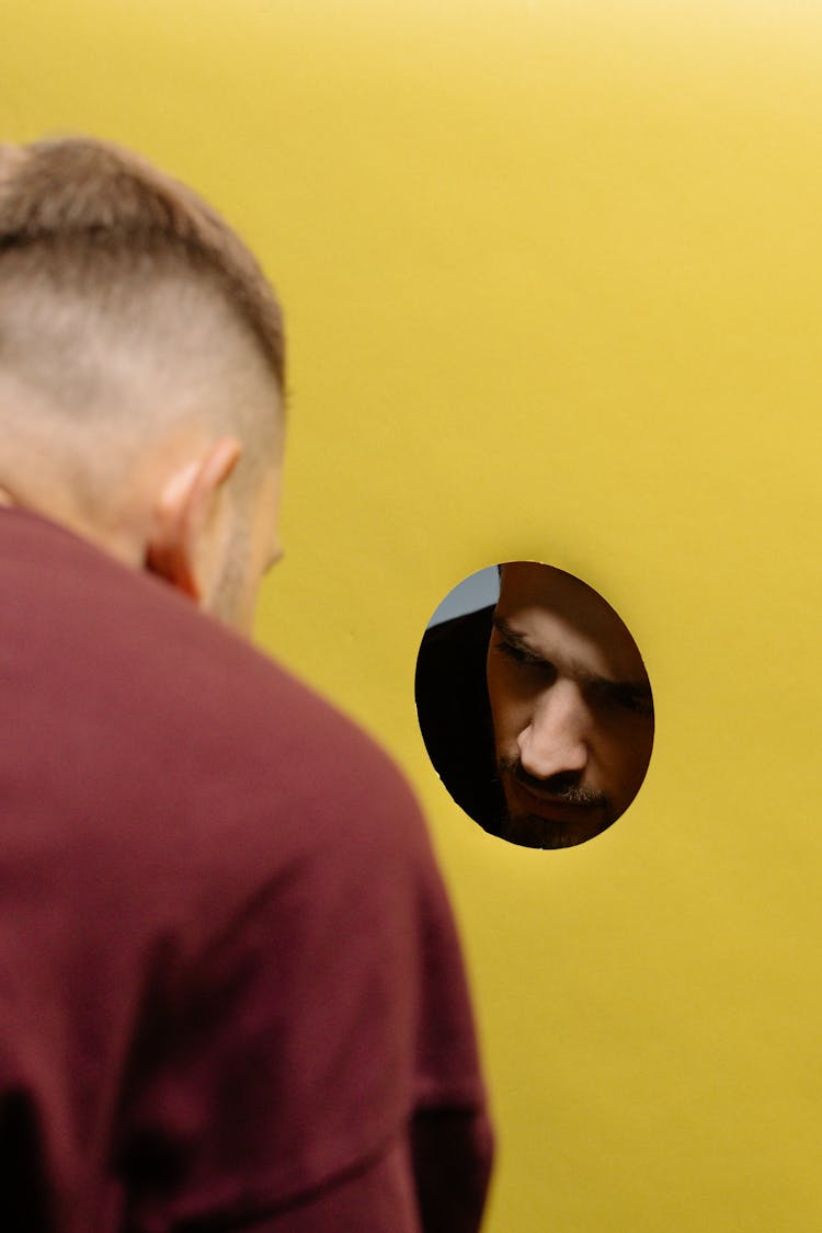 Men Looking Though A Hole In A Yellow Wall 