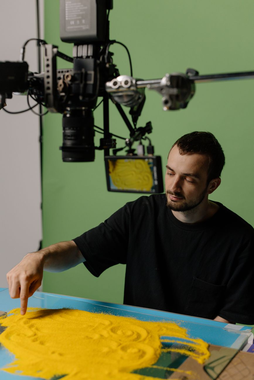 Artist working on art project with camera setup in studio.