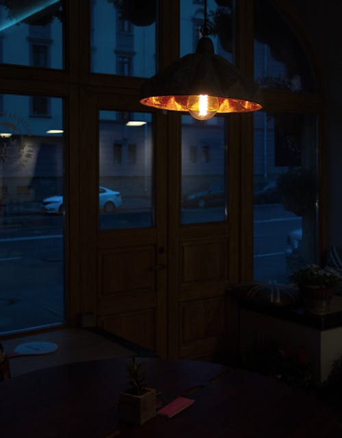 Free Glowing hanging lantern illuminating dark building near entrance door and city road at dusk Stock Photo