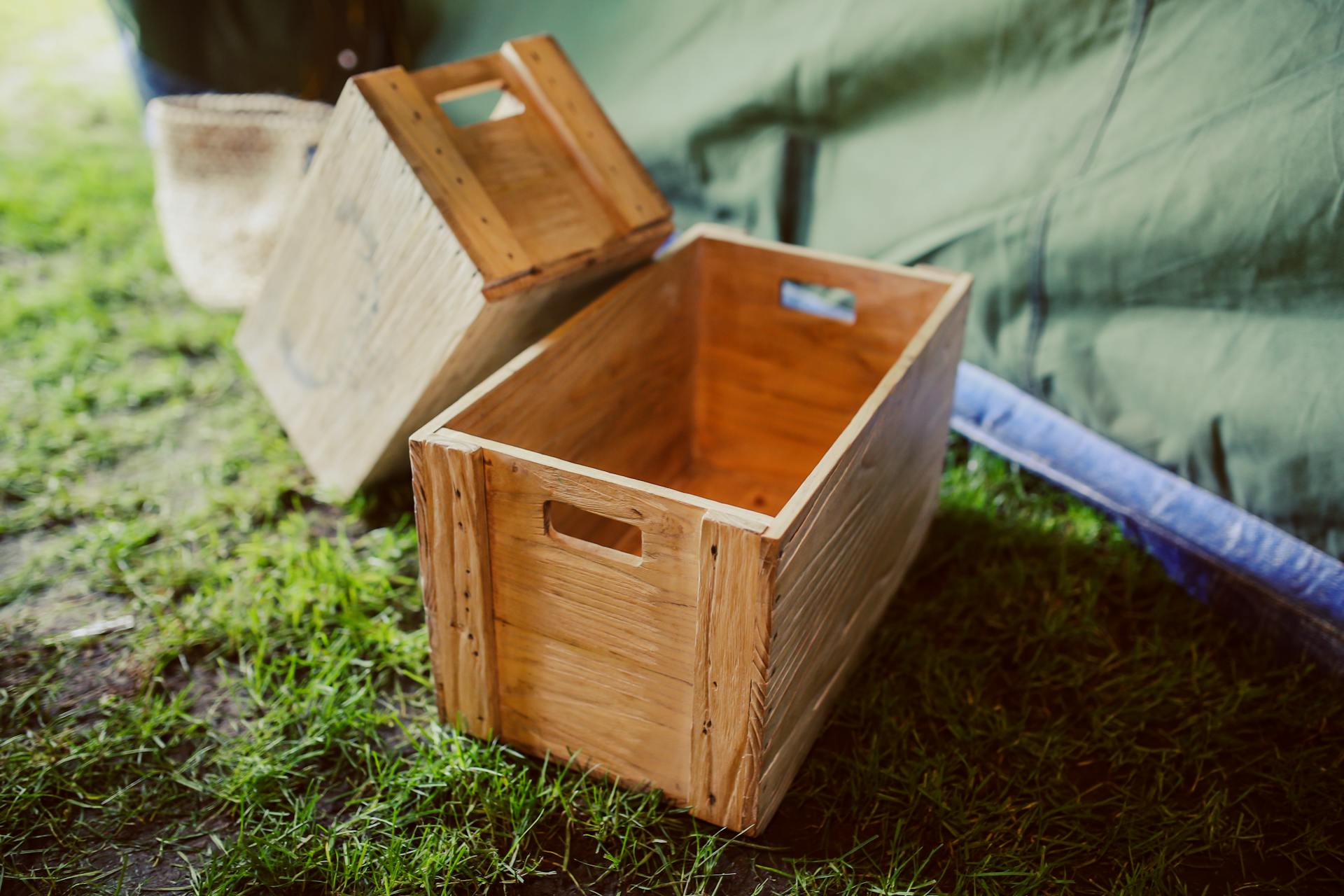 Rustic wooden crates placed on grass in a rural outdoor setting, perfect for garden decor.