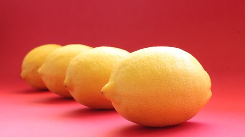 Free Close-up of fresh yellow lemons arranged against a vivid red backdrop, highlighting natural texture. Stock Photo