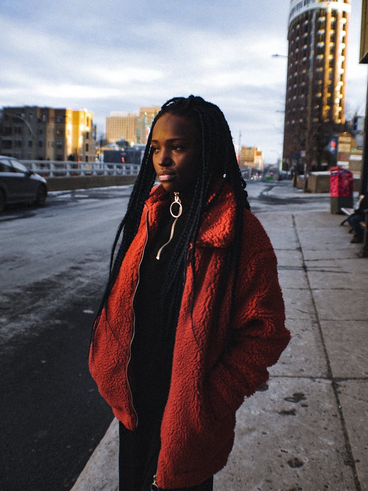 Woman In Red Fleece Coat Standing On The  Sidewalk