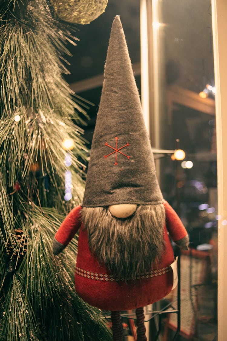 Decorative Dwarf Against Christmas Tree With Garland Indoors