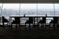 透过一扇大窗户，时尚的休息室俯瞰着广阔的城市景观，营造出宁静而雾气缭绕的氛围