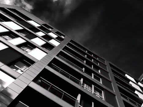 一张引人注目的黑白照片以低角度捕捉了现代建筑与戏剧性的天空