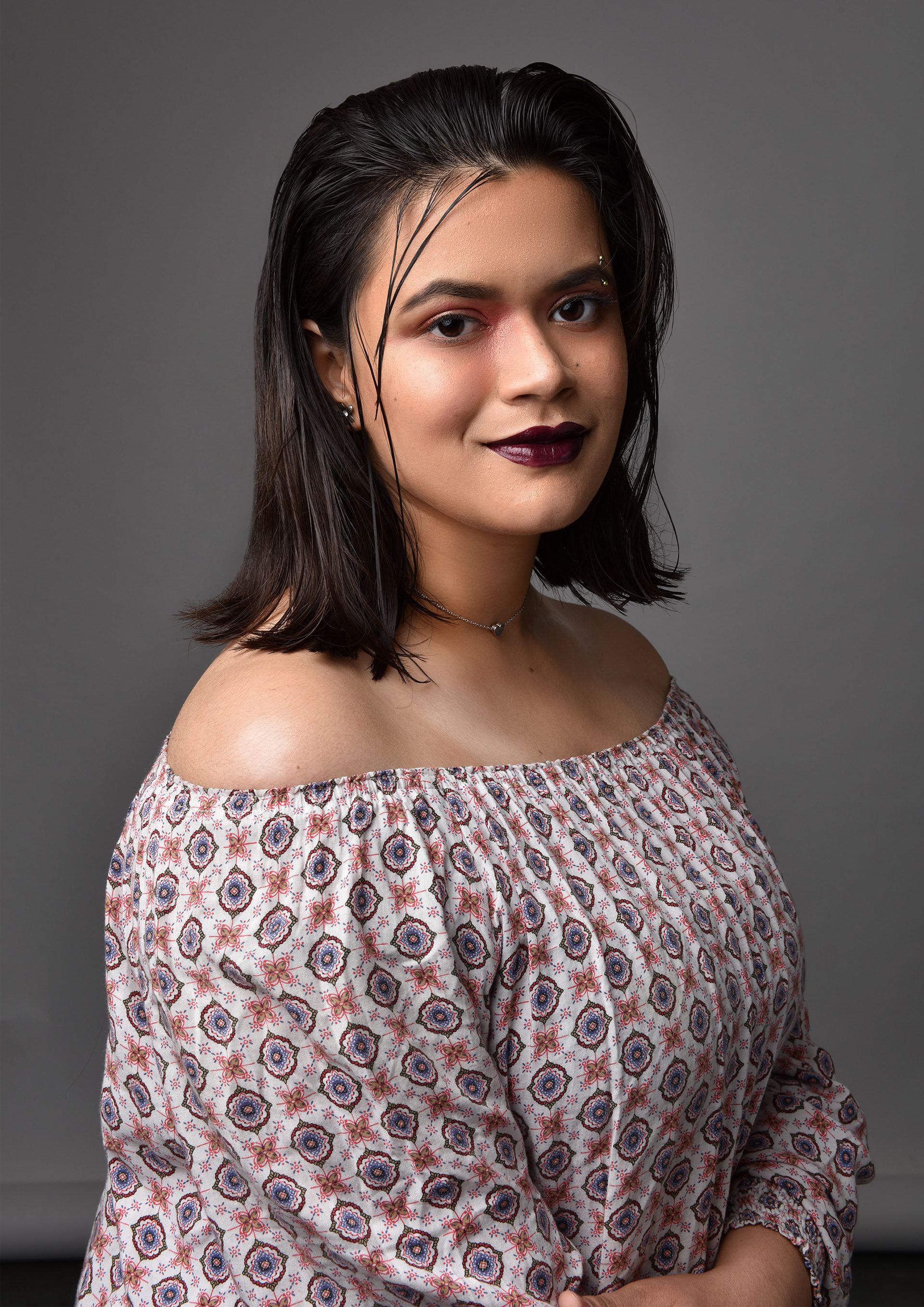 Charming portrait of a woman with a floral blouse, smiling confidently.