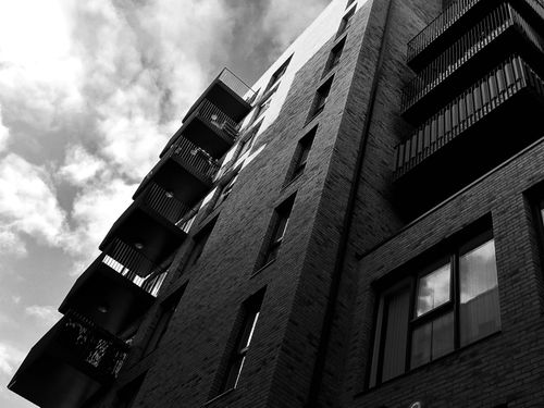 Free Low angle view of a modern urban building with balconies against a cloudy sky, enhancing the dramatic facade. Stock Photo
