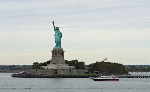 Free The iconic Statue of Liberty with a tour boat passing by in New York City. Stock Photo