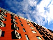 低角度视角下，红色建筑立面与几何窗户在明亮的蓝天下相映成趣