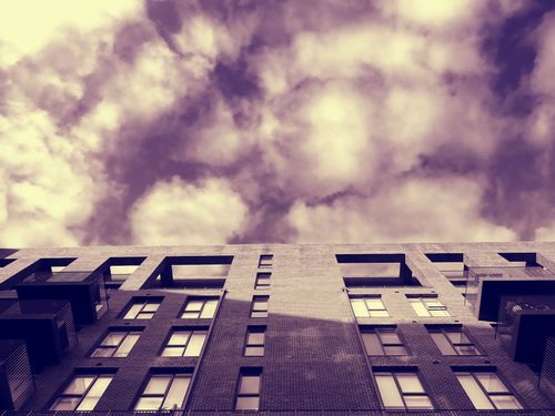 Free Low angle view of modern architecture against a dynamic sky, featuring clouds and reflections. Stock Photo