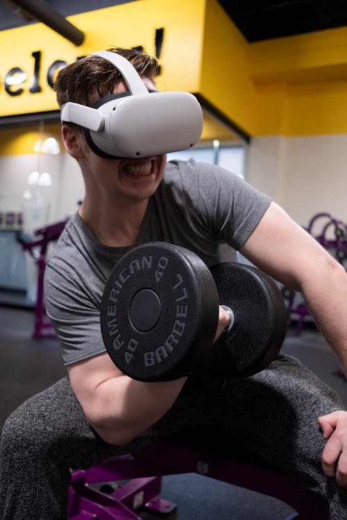 Free A Man Lifting Dumbbell while Wearing Virtual Goggles Stock Photo