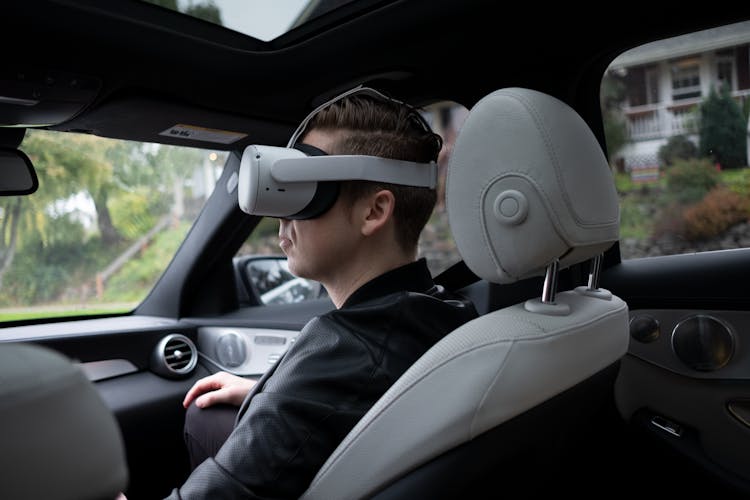 A Man Wearing Virtual Reality Goggles While Riding A Car