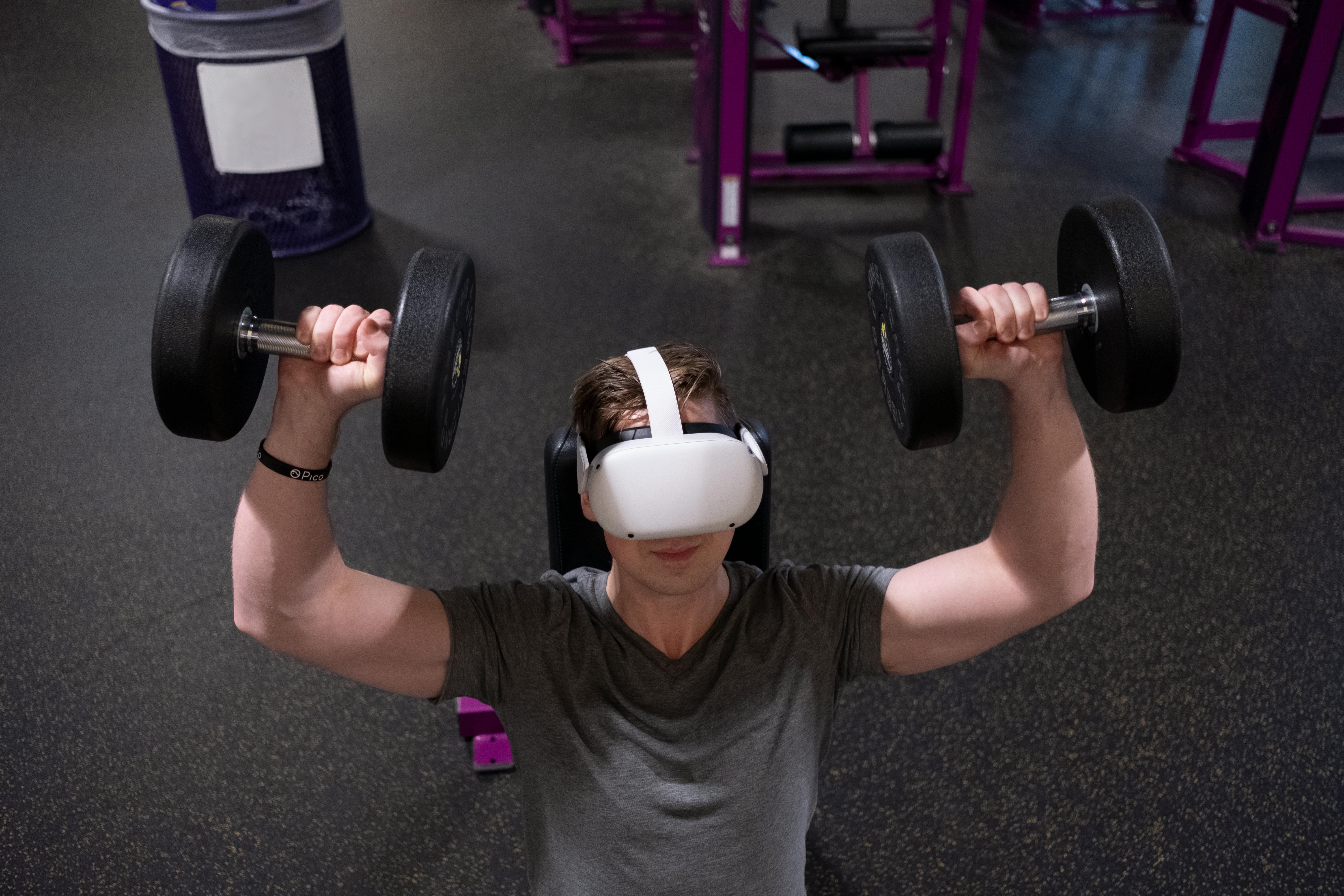 a man lifting dumbbells while wearing virtual reality goggles