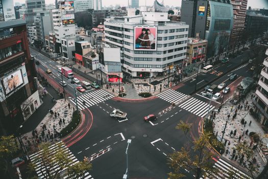Aerial view showcasing a busy Tokyo intersection with pedestrians, vehicles, and urban buildings.