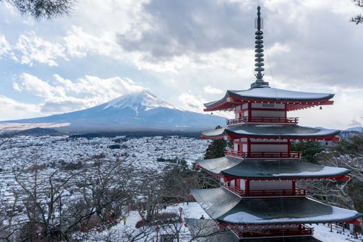 Chureito Pagoda with a backdrop of snow-capped Mount Fuji under a cloudy winter sky in Fujinomiya, Japan.