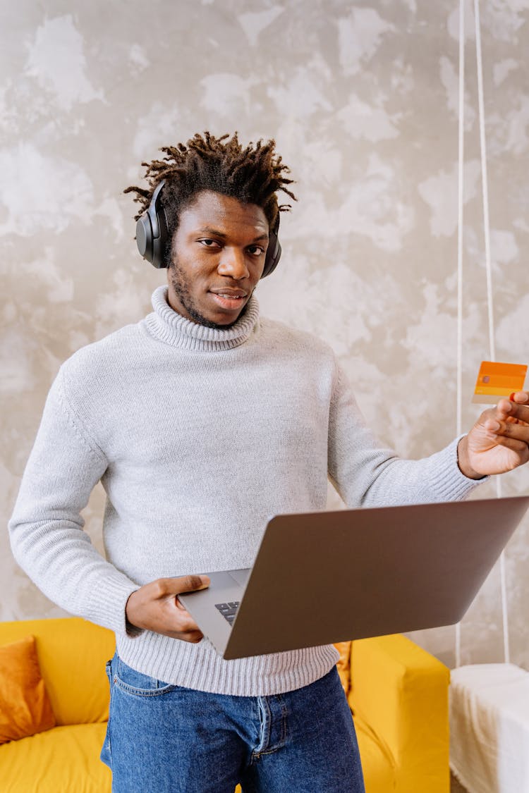 A Man Standing While Holding A Laptop