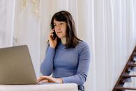 在舒适的室内环境中，年轻女性使用智能手机和笔记本电脑进行多任务处理