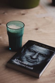 High angle shot of a book and frothy coffee on a wooden table. — photo by Sergei Bezborodov