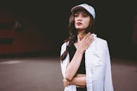 在黑暗背景下，一位自信的年轻女子穿着休闲街头服装在户外摆姿势