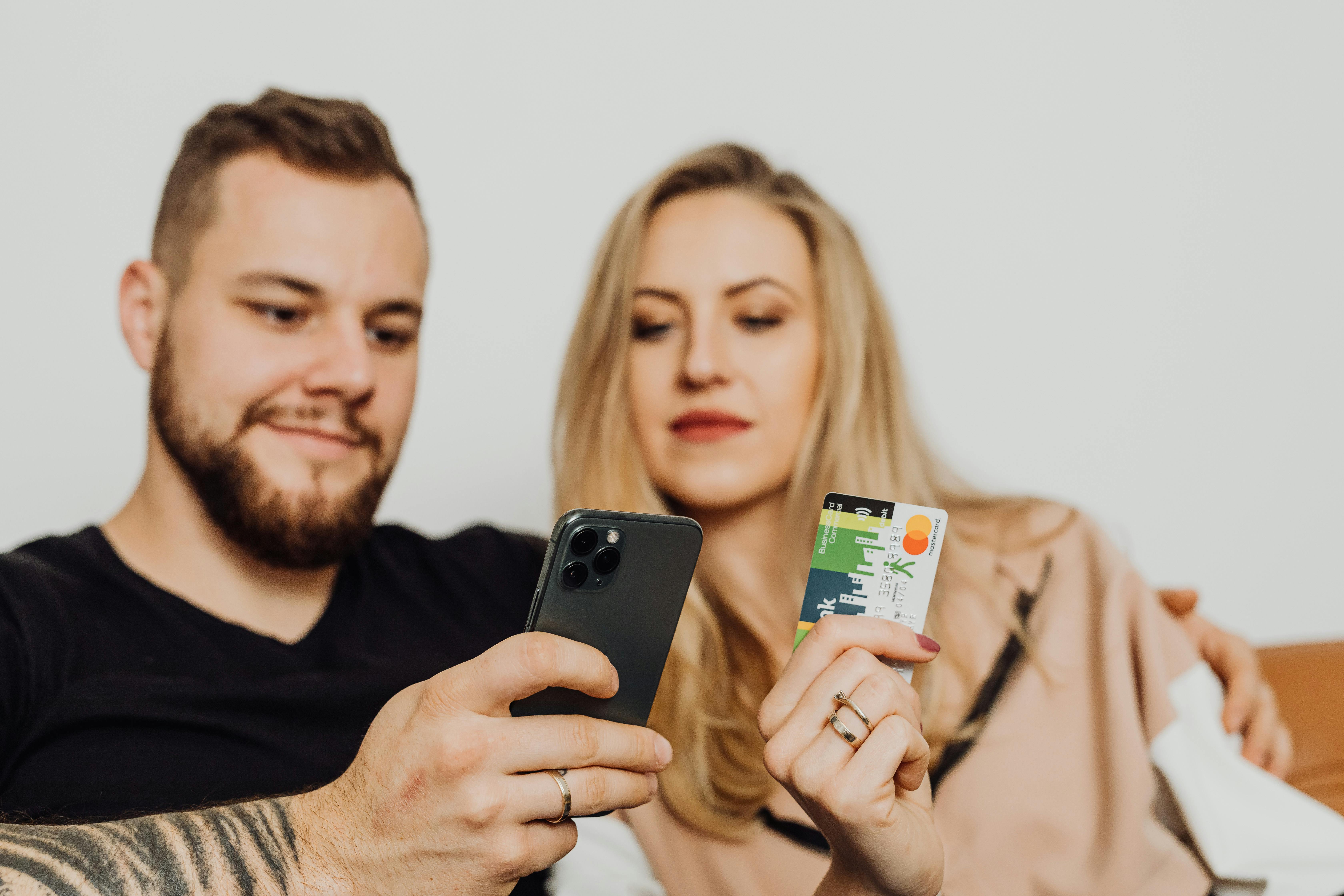 couple using smartphone while holding a bank card