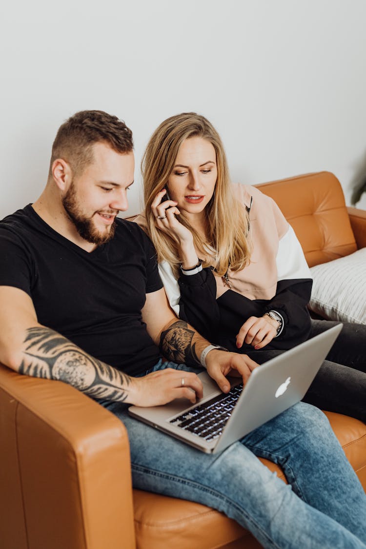 Couple On Sofa Looking At Laptop