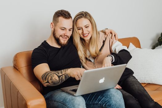 一对幸福的情侣在室内沙发上，一起用笔记本电脑享受时光