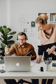 A man and woman collaborate on a project at a minimalist home office desk.