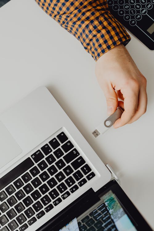 Free A Person Putting a USB Flash Drive on a Laptop Stock Photo
