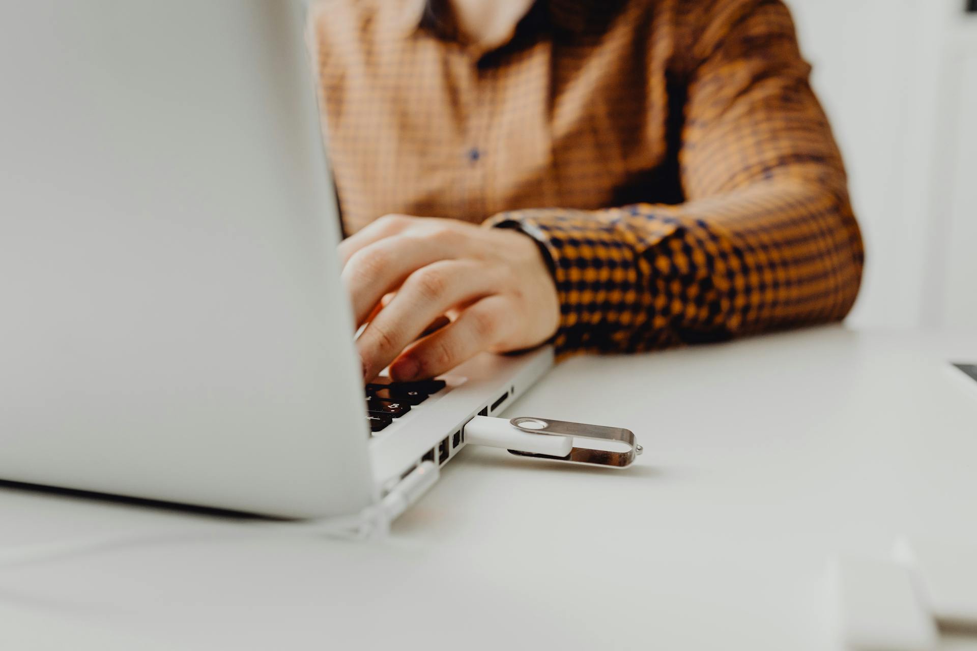 A person working on a laptop with a USB flash drive connected, representing technology and data storage.