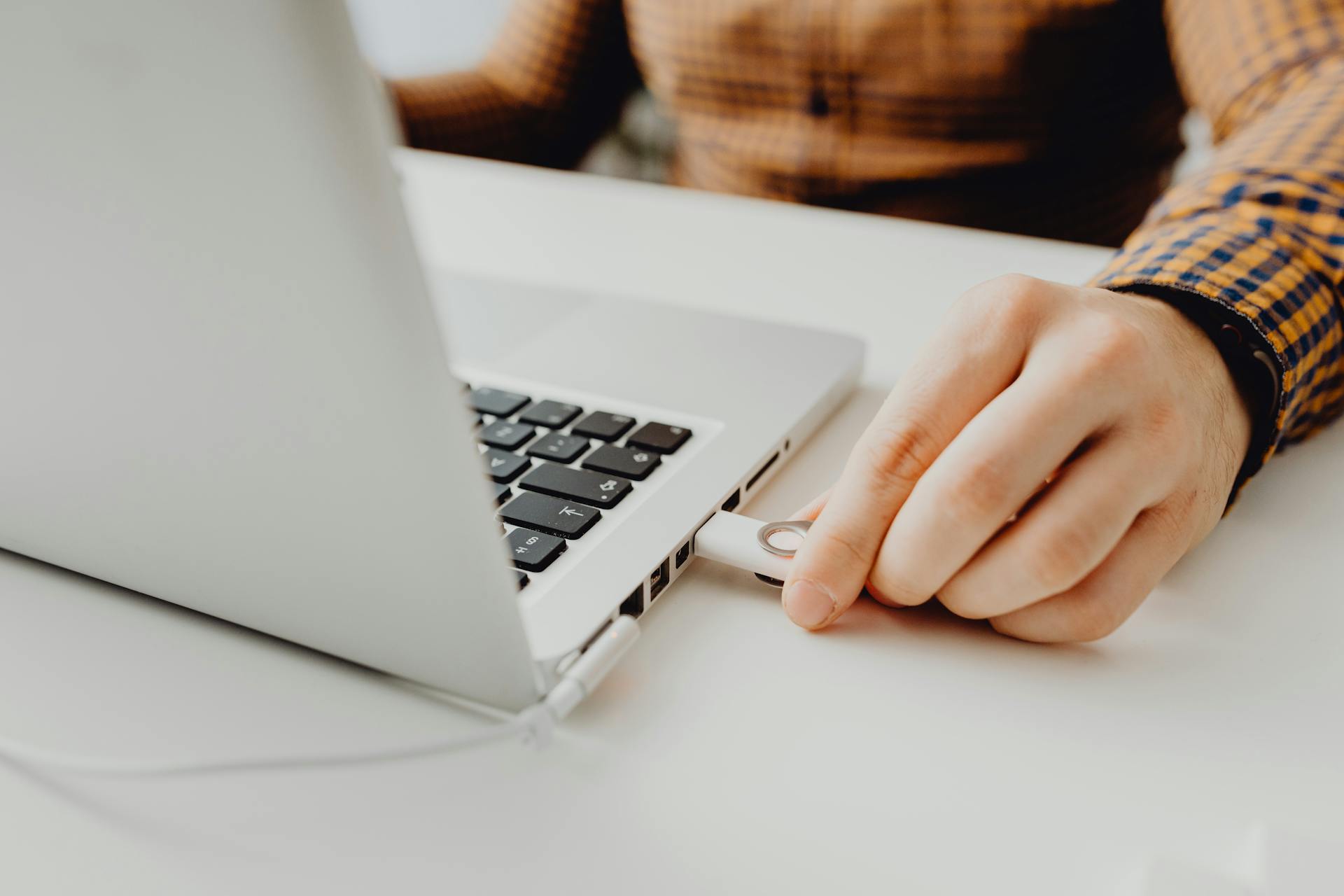 Photo of a Person's Hand Plugging in a Flash Drive into a Laptop