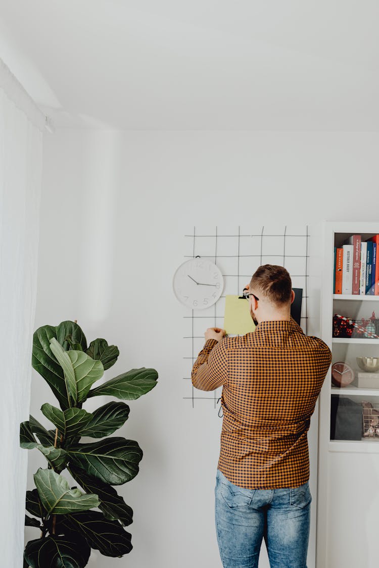 A Man Posting A Paper On A Grid On The Wall