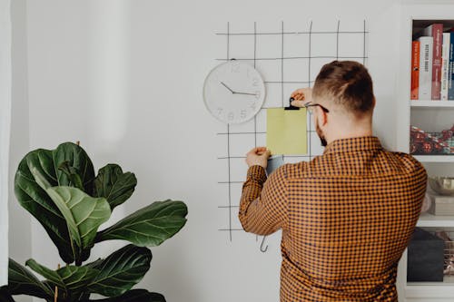 A Man Clipping a Yellow Paper on the Wall Grid