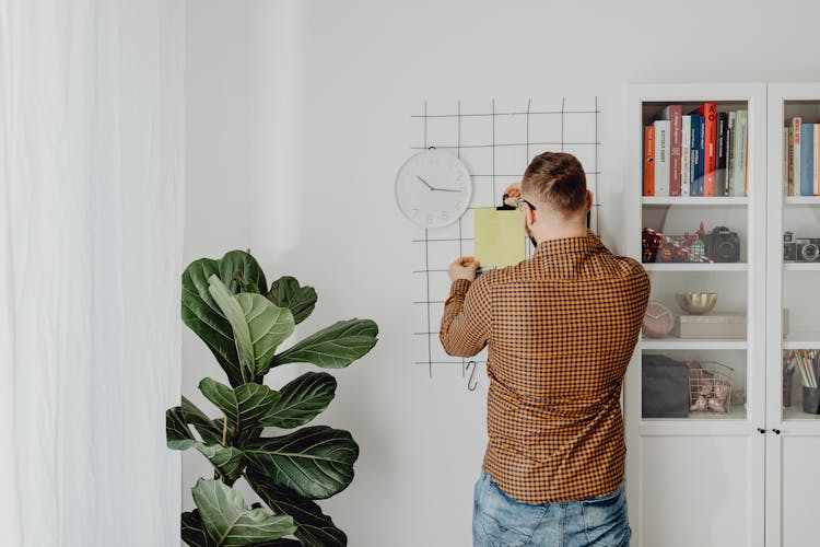 A Man Posting A Note On The Wall Grid