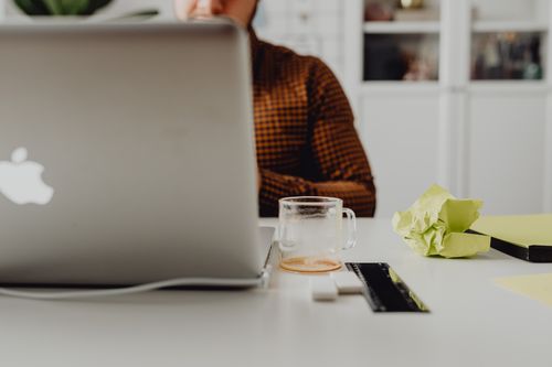 Free Office workspace with a person using a laptop and coffee cup, promoting productivity. Stock Photo