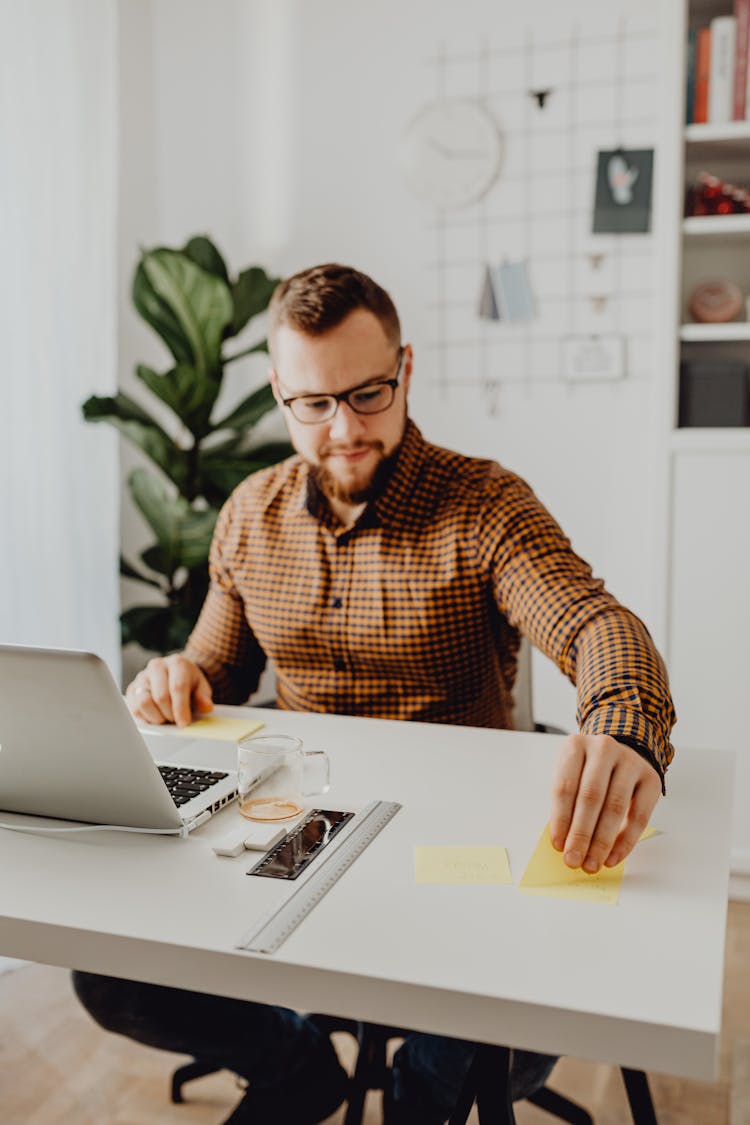 A Man Posting Sticky Notes On His Desk