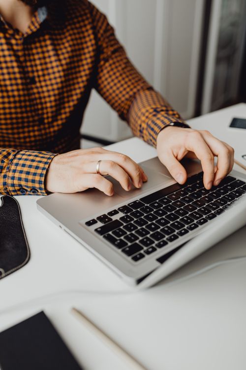 Free A man typing on a laptop in a modern office setting, showcasing technology and work life. Stock Photo