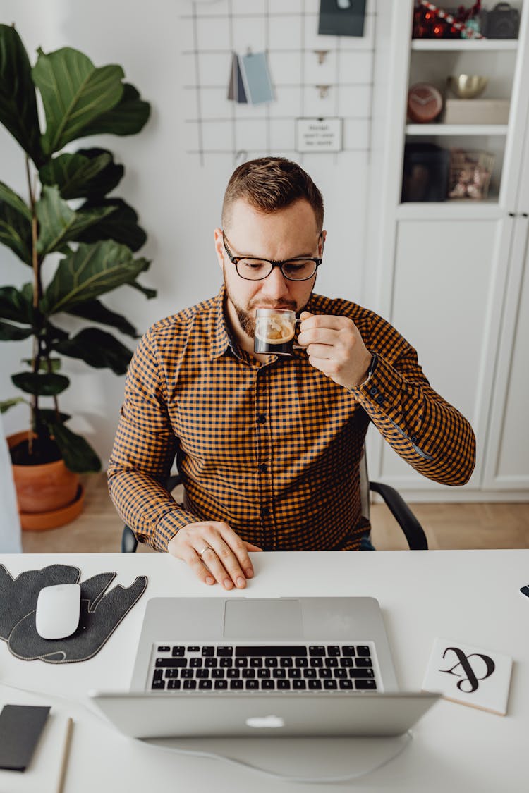 A Man Drinking Coffee While Using Laptop