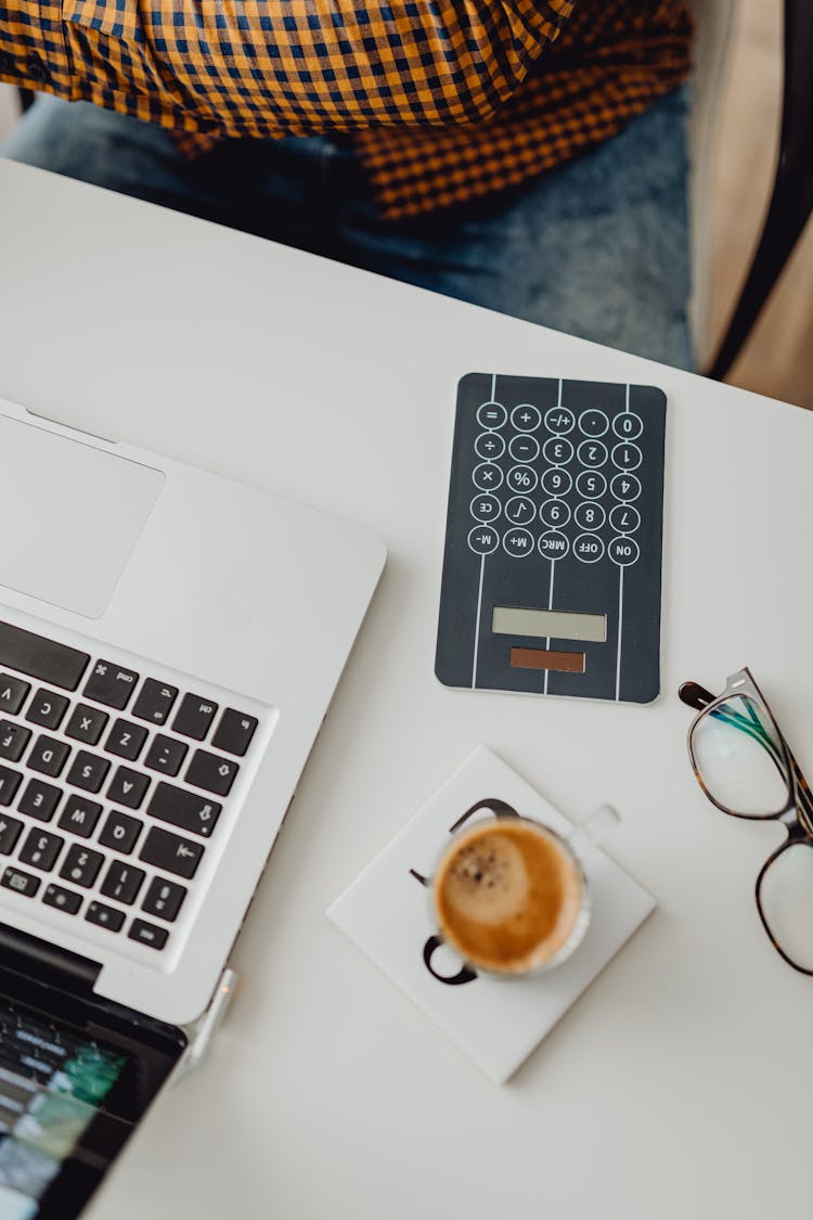 Calculator And Laptop On White Desk