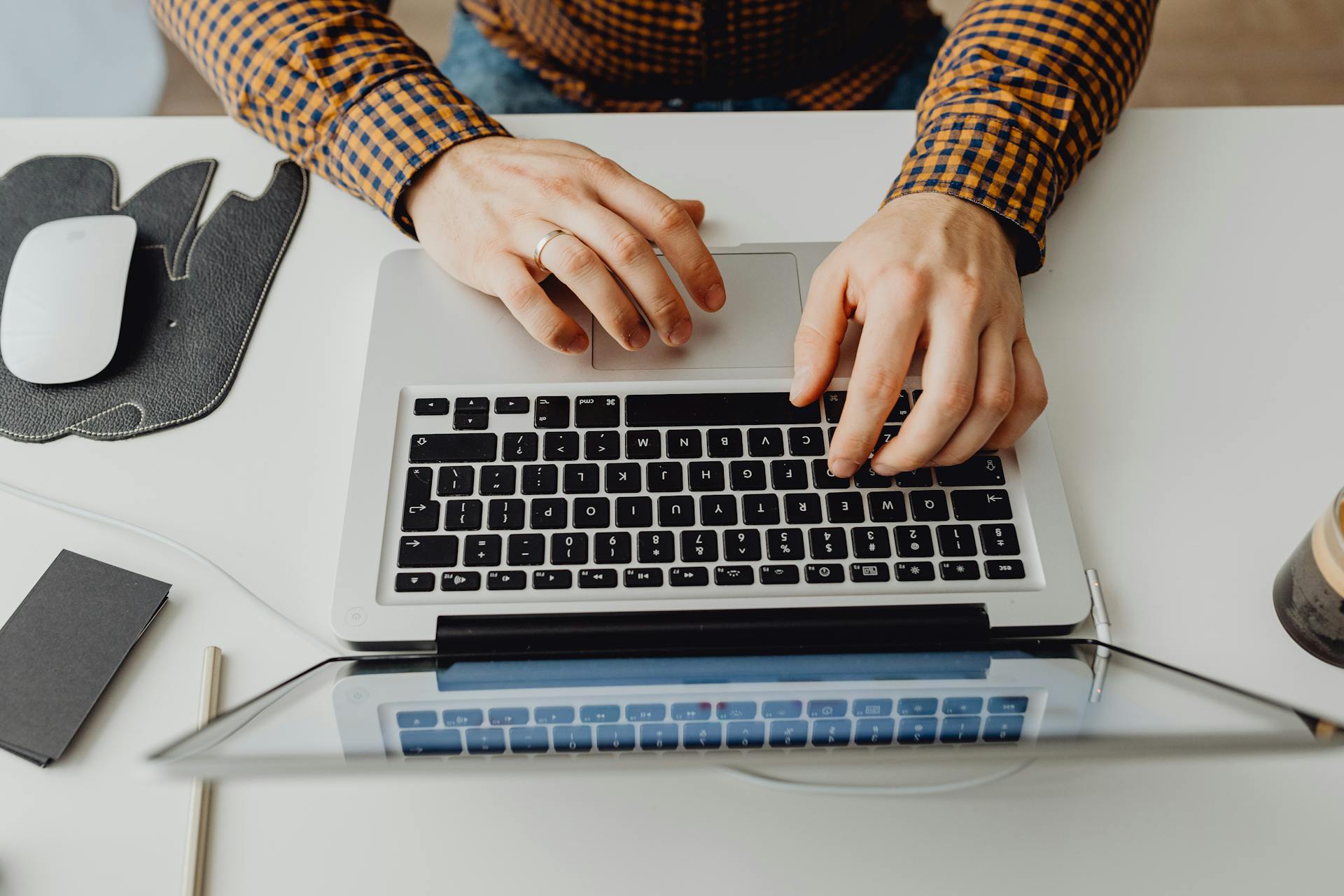 Hands typing on a laptop keyboard in a modern home office environment.