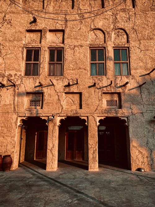 Free A sunlit stone facade of a historic building with arched windows and entrances. Stock Photo