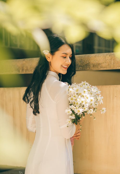 A Pretty Woman in White Dress Holding a Bouquet of White Flowers