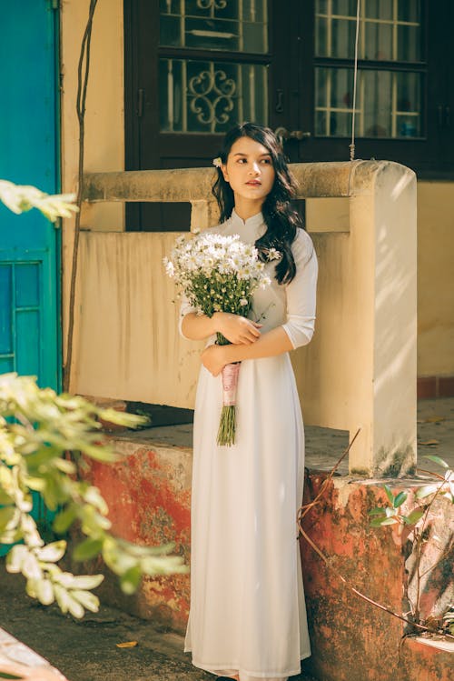 A Pretty Woman in White Dress Holding a Bouquet of White Flowers
