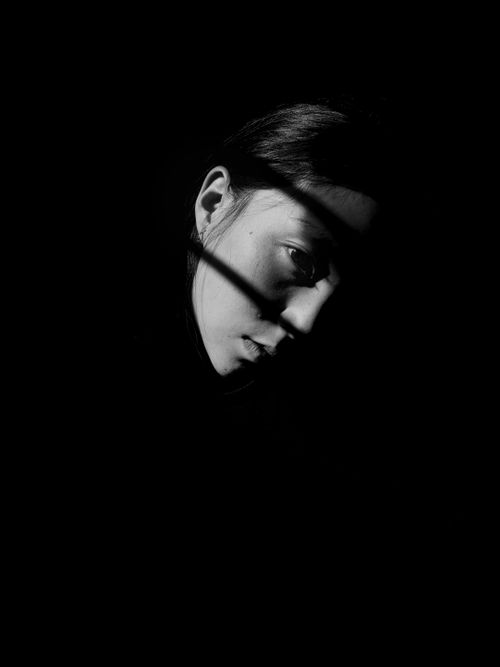Free Black and white portrait of a woman partially obscured by shadows, evoking mystery. Stock Photo