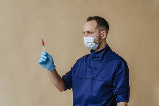 男性医护人员戴着口罩和手套，手持注射器接种疫苗
