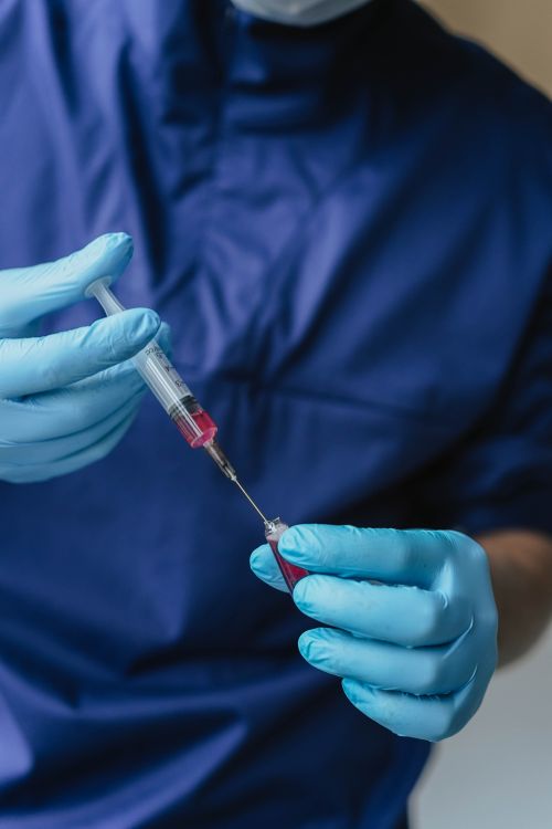 Free Close-up of a healthcare worker handling a syringe with medical gloves. Stock Photo