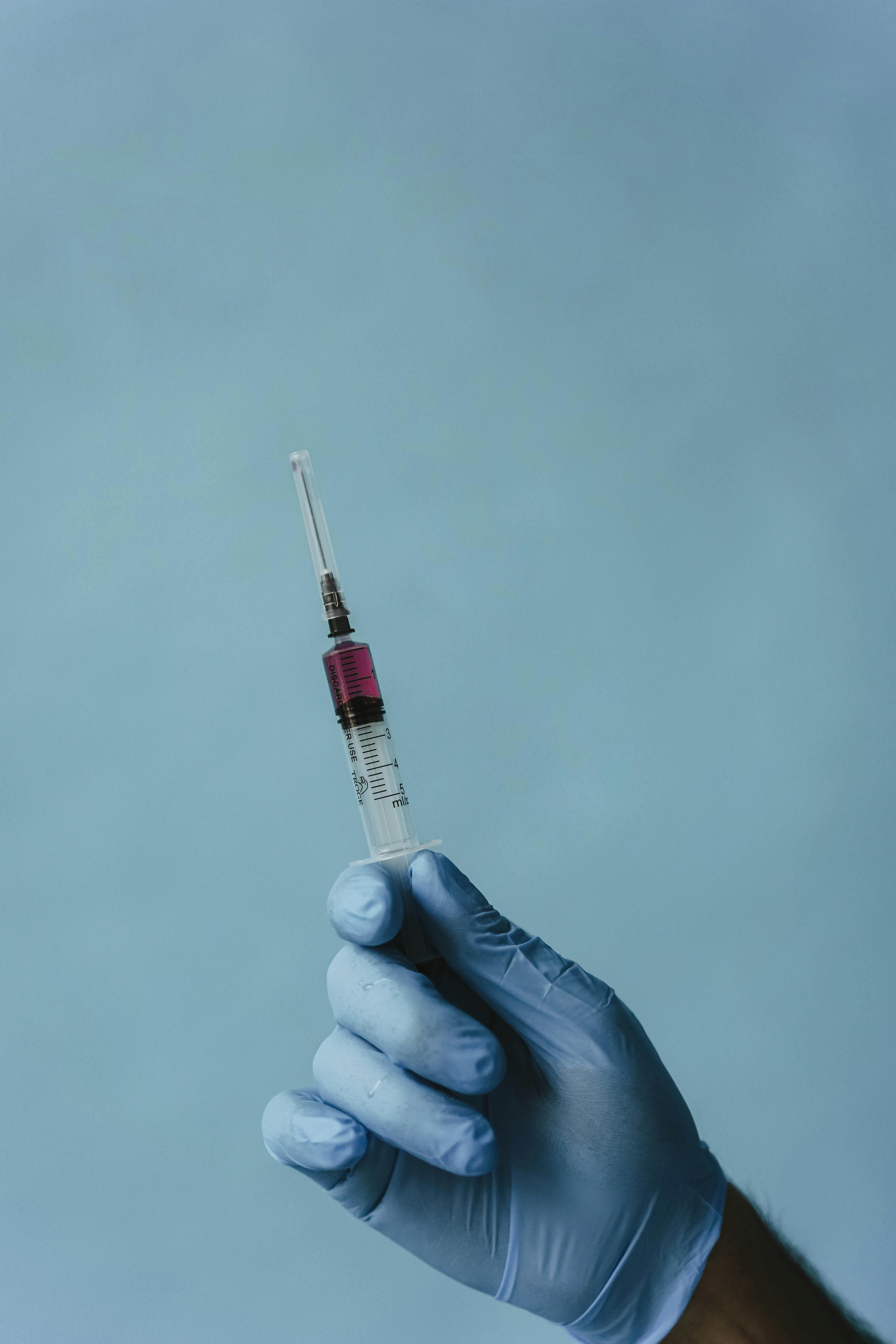 一只戴着手套的手拿着注射器，背景是普通的医疗环境