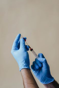 一只戴着手术手套、手持注射器进行医疗操作的手部特写