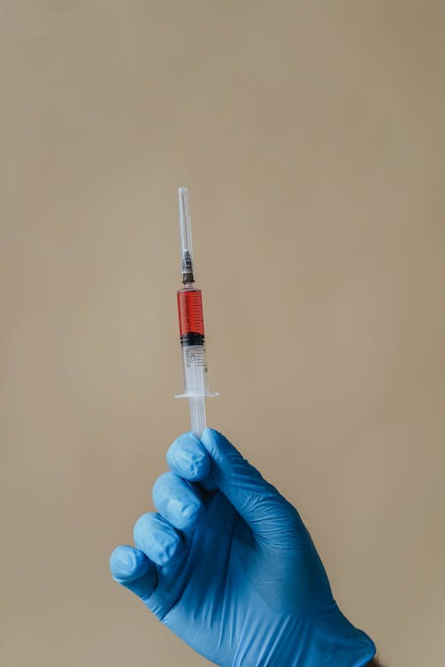 Close-Up Shot of a Person Holding a Syringe 