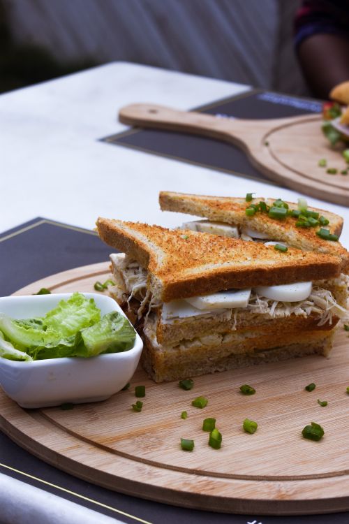 Free Appetizing toasted sandwich with garnished lettuce served on a wooden board. Stock Photo