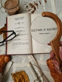 A cozy scene with a book, coffee, and a magnifying glass on a textured background. — photo by Ena Marinkovic